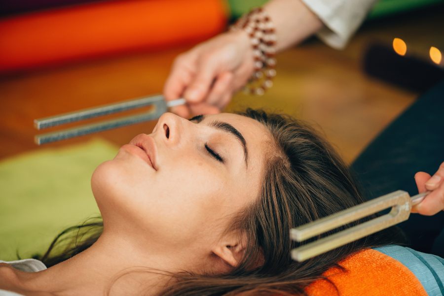 Woman in a session of Tuning Forks at the ears that induces a deep relaxation, calming the activity of the mind