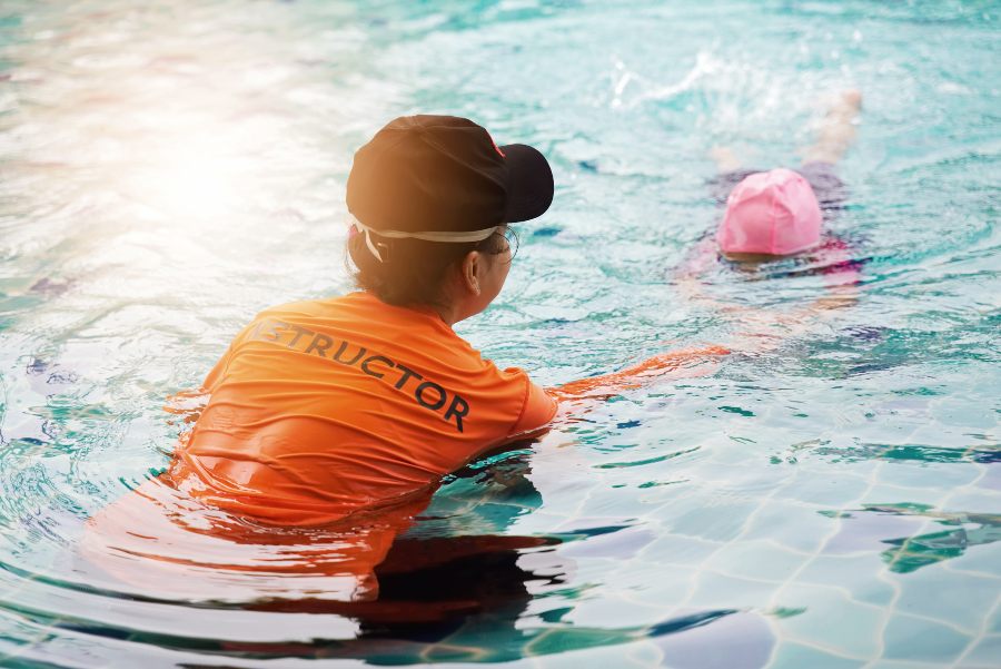 Female instructor teaches kid how to swim