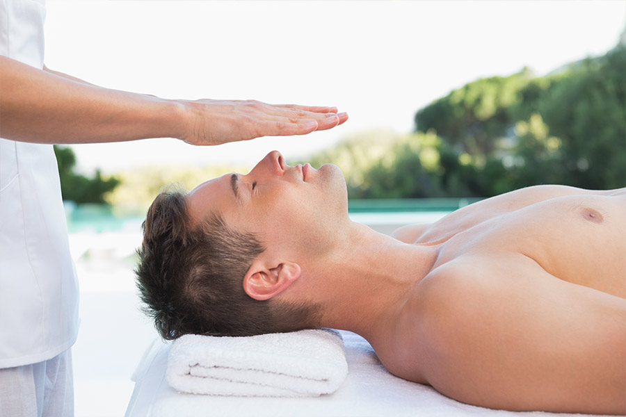 Thearapist performing reiki on young woman